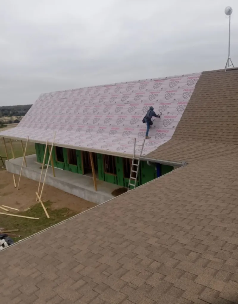 Worker preparing underlayment for a metal roof installation in Allouez